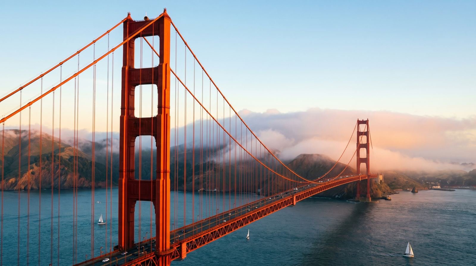 The Golden Gate Bridge in San Francisco at golden hour with fog rolling in around the towers